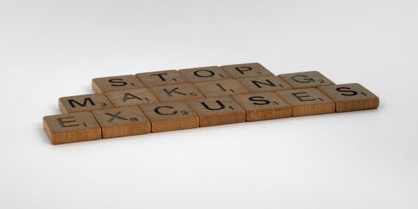 Inspirational phrase "Stop making excuses" crafted with wooden letter tiles.